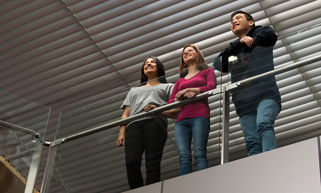 3 student looking out from a balcony